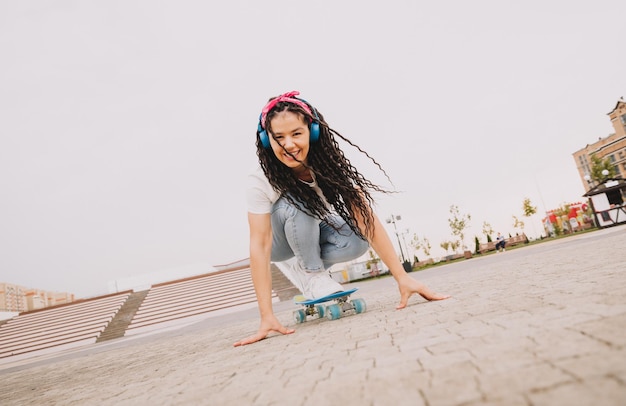 Photo a beautiful young girl with dreadlocks rides a skateboard in sunny weather generation z