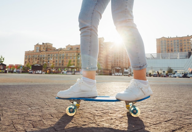 A beautiful young girl with dreadlocks rides a skateboard in sunny weather generation z