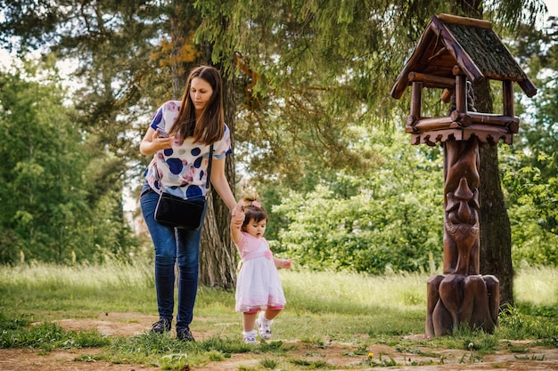красивая и молодая девушка со своей маленькой девочкой на прогулке, играя в парке на открытом воздухе возле леса