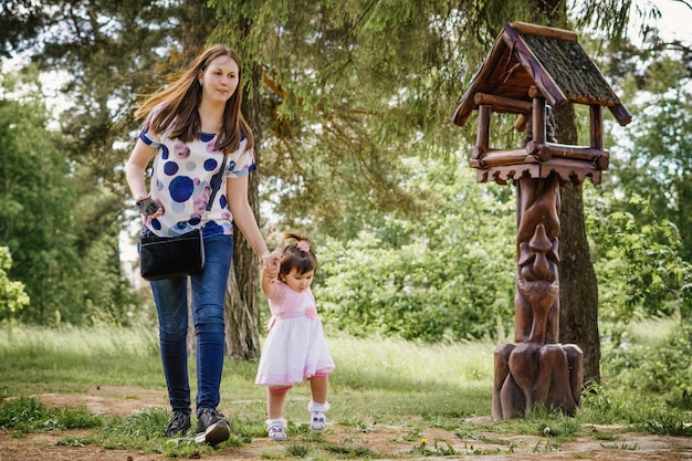 森の近くの屋外の公園で遊んで散歩のための彼女の小さな女の子と一緒に美しく若い女の子