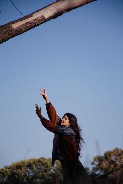 Beautiful young girl with long hair dancing against the blue sky.