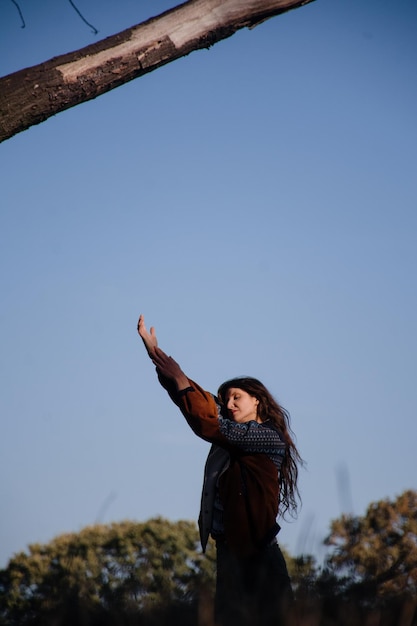 Beautiful young girl with long hair dancing against the blue sky.