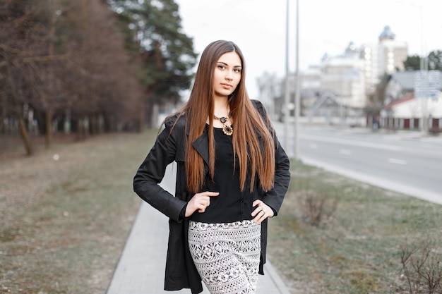 Beautiful young girl with long hair in a stylish black coat