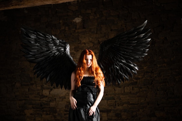 暗い部屋で長い赤い髪と黒い翼を持つ美しい若い女の子