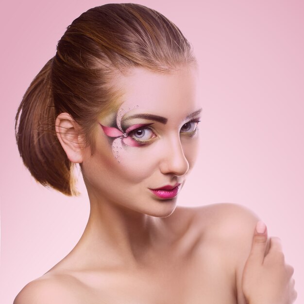 Beautiful young girl with make up looking at front on pink