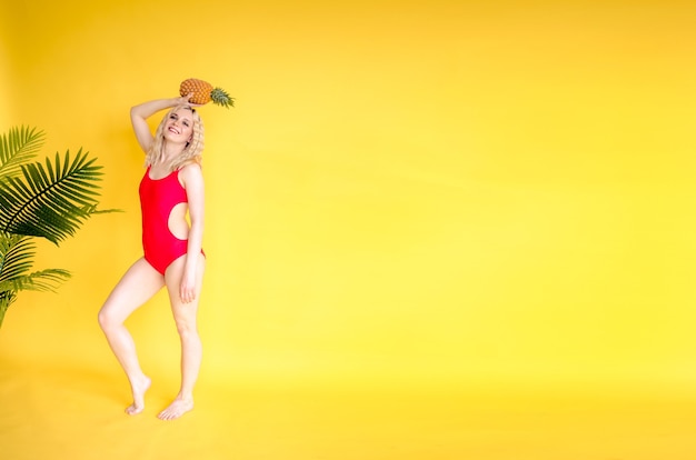 Foto una bella ragazza con ananas vicino a uno sfondo giallo concetto di cibo sano