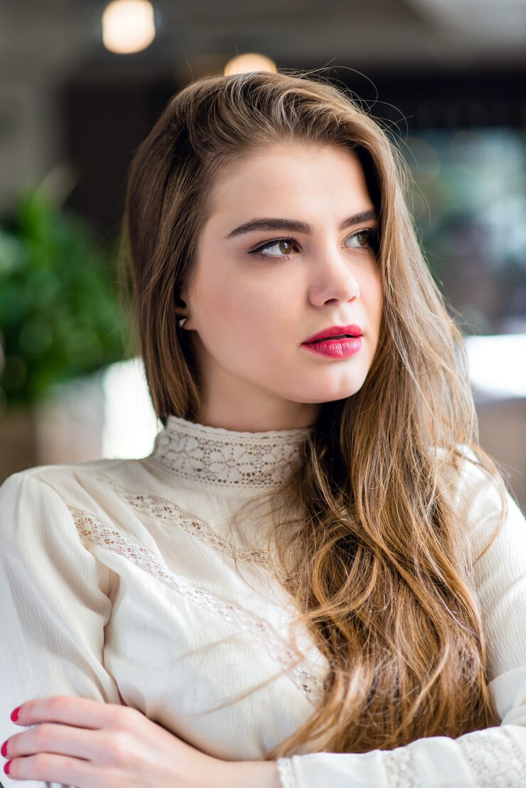Photo beautiful young girl with professional makeup and hairstyle sitting in restaurant.