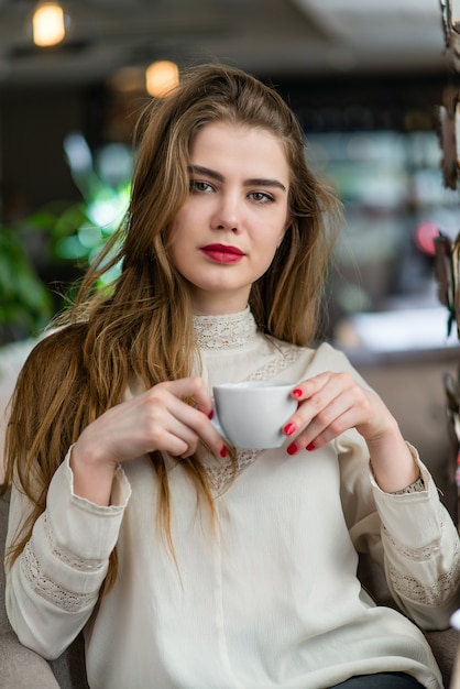 Beautiful young girl with professional makeup and hairstyle sitting in restaurant.