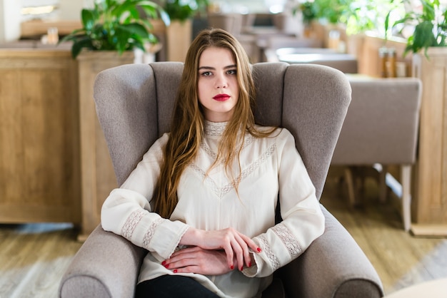 Beautiful young girl with professional makeup and hairstyle sitting in restaurant.