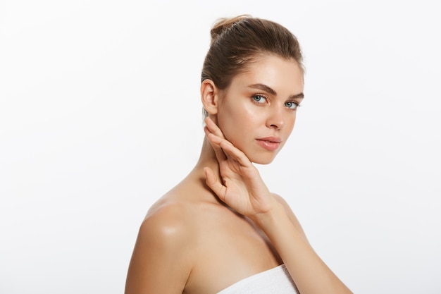 Beautiful young girl with smooth skin on a light background with natural make-up