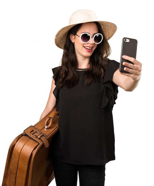 Beautiful young girl with  a suitcase making a selfie