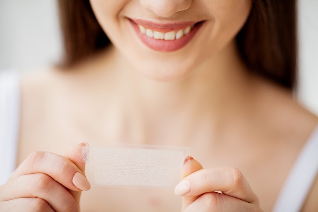 Beautiful Young Girl With White Teeth Holding in Hands Stripes For Teeth Whitening. 