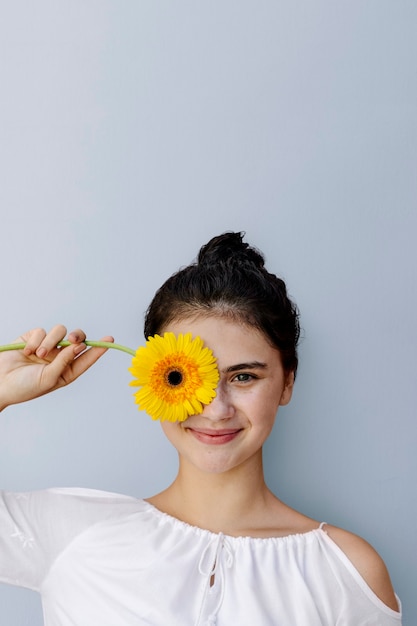 Foto bella ragazza con un fiore di gerbera gialla