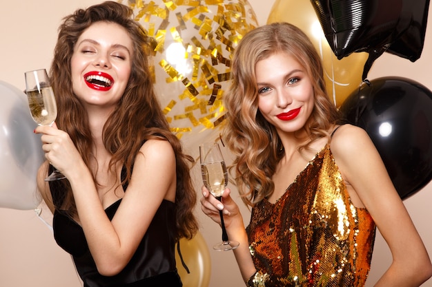 Beautiful young girls in elegant evening dresses with festive balloons. Beauty face. Photo taken in the studio