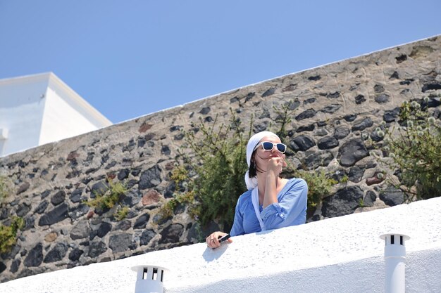 Beautiful young Greek woman in fashion clothes have fun at n the streets of Oia, Santorini, Greece