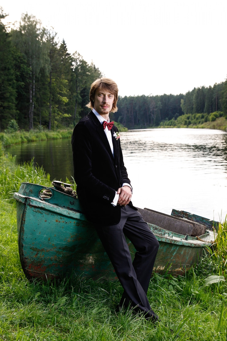 Photo beautiful young groom sitting on boat