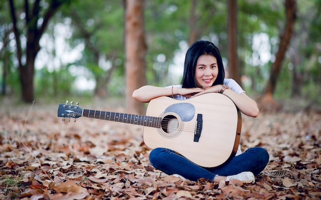 Beautiful young guitarist Playing guitar happily in the garden, nature forest, music concept