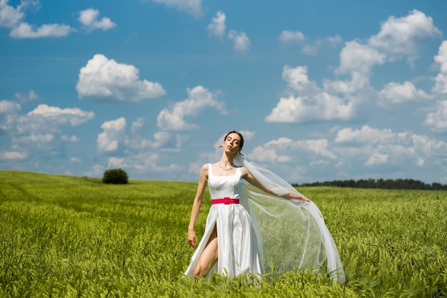 Beautiful young happy bride on green field