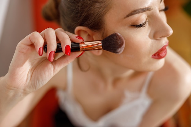 Beautiful young happy caucasian woman at cozy home with cosmetics at sunny morning