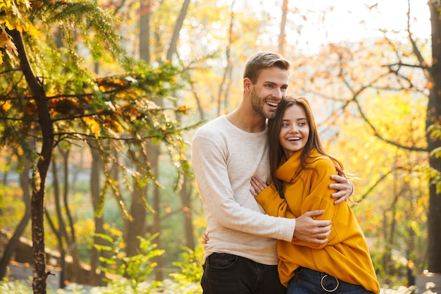 秋の公園で時間を過ごしながら抱きしめる愛の美しい若い幸せなカップル