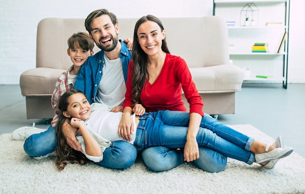 Bella giovane famiglia felice seduta sul pavimento a casa e divertirsi