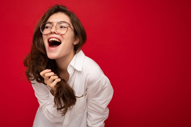 Beautiful young happy joyful funny curly brunette woman wearing white shirt and optical glasses