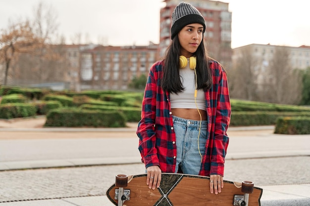 Beautiful young hipster woman posing with skateboard Hispanic Latin woman wearing casual clothes