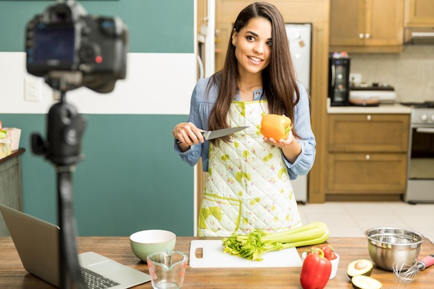 Beautiful young Hispanic brunette giving some cooking advice on her video blog at home