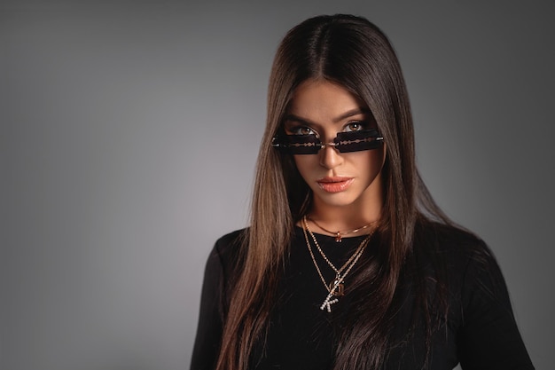 Beautiful young lady in a black turtleneck with massive jewelry\
and extraordinary sunglasses