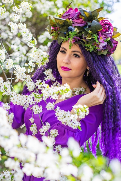 Bella giovane donna nel giardino dei fiori di ciliegio