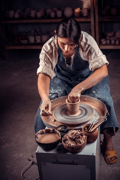 Bella giovane signora che fa ceramiche, scultore di argilla bagnata sulla ruota. produzione artigianale.