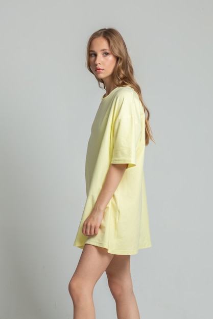 Beautiful young lady posing in profile in a long yellow tshirt