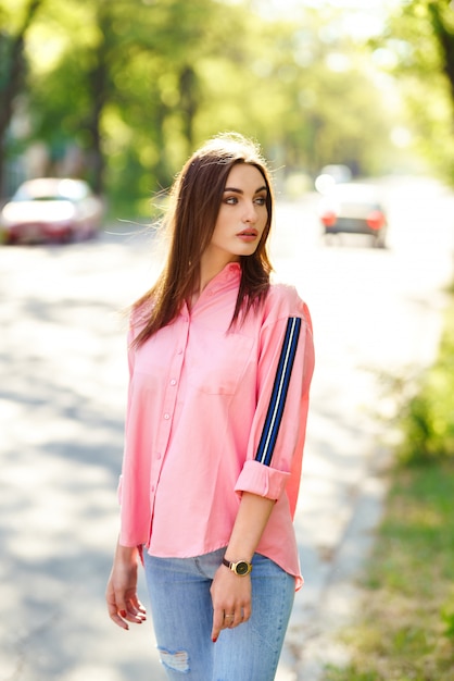 Beautiful young lady with long healthy hair and cute dress walking on the street. Hot summer evening. Sunset. Lifestyle concept.