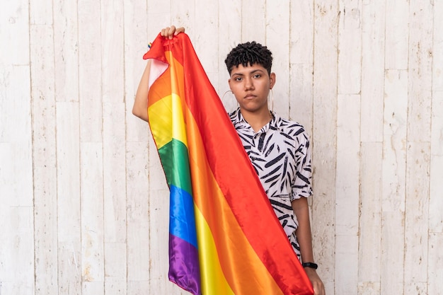 Photo beautiful young lgbt woman posing with rainbow flag on the street