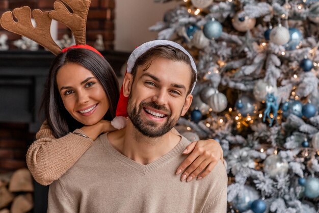 Photo beautiful young loving couple bonding and smiling while celebrating new year with look in camera