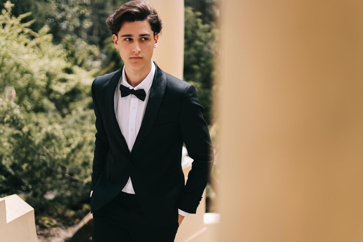 Photo 一位漂亮的年轻人,新郎穿着优雅的婚<unk>服,站在城市的旧公园中摆姿势