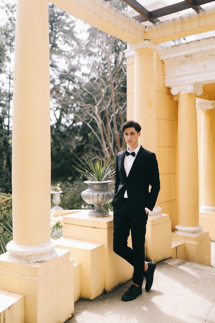 Photo 一位漂亮的年轻人,新郎穿着优雅的婚<unk>服,站在城市的旧公园中摆姿势
