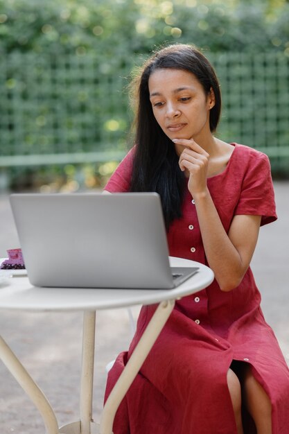 Beautiful and young millennial african woman in a public place working on a laptop