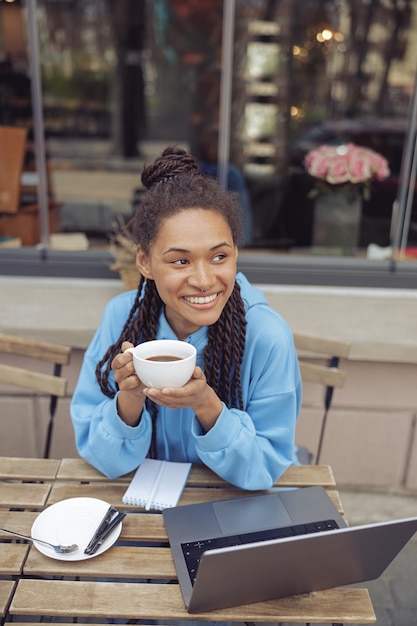 Beautiful young mixedrace stylish woman with piercing holding coffee smiling Top view