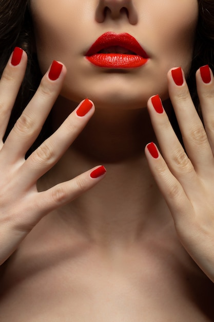 Beautiful young model with red lips and red manicure