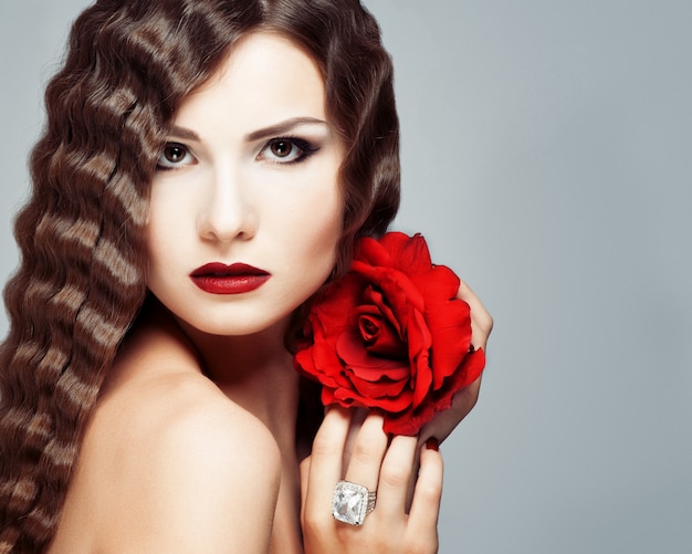 Beautiful young model with red lips and red rose