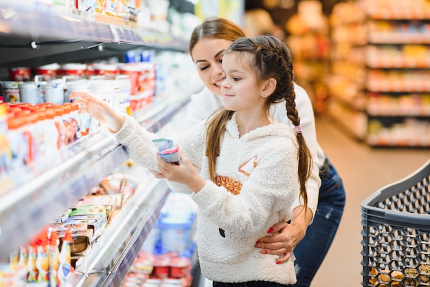 Beautiful young mom and her little daughter smiling and buying food 