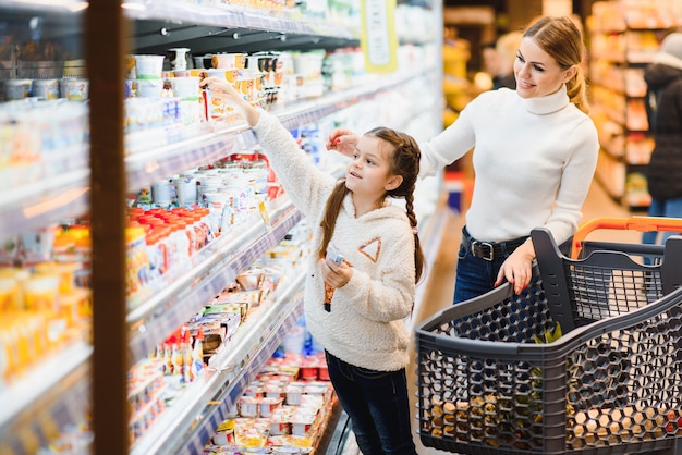 Bella giovane mamma e la sua piccola figlia sorridente e l'acquisto di cibo