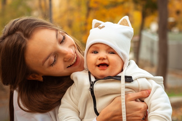 Beautiful young mom with baby girl in autumn