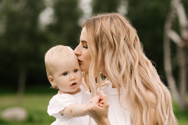 Beautiful young mom with one-year-old daughter in nature