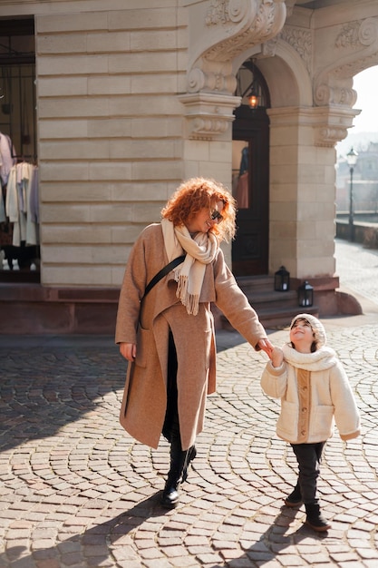 美しい若い母親と 4 歳のかわいい小さな娘がヨーロッパの旧市街の中心部を歩いている幸せな家族