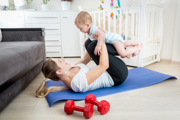 彼女の男の子と一緒に床で運動する美しい若い母親