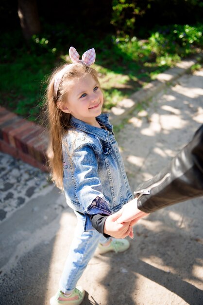 Bella giovane madre e la sua adorabile figlia piccola, carina bambina riccia che gioca e cammina in giardino in una soleggiata giornata primaverile.