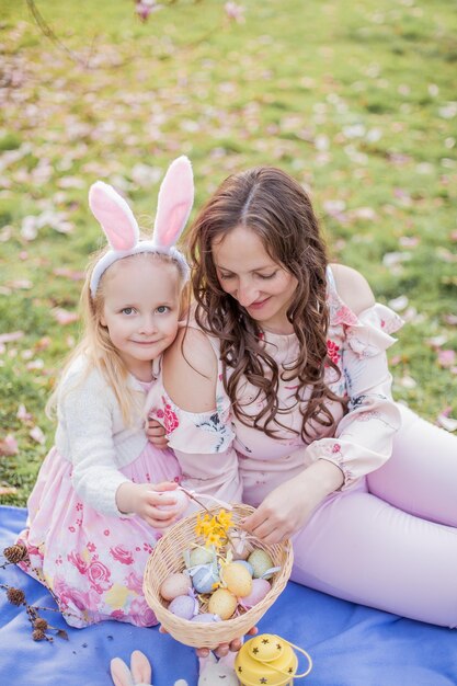 Photo beautiful young mother and little daughter near a blooming magnolia. easter. spring. pink blooms.