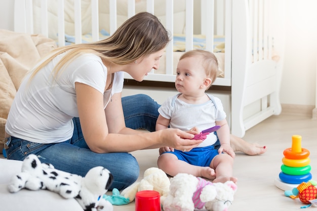 Bella giovane madre che gioca con il suo bambino sul pavimento